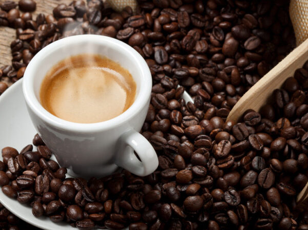 immagine di una tazza di caffè fumante con i chicchi di caffè vicino