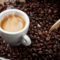 immagine di una tazza di caffè fumante con i chicchi di caffè vicino